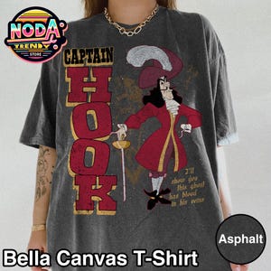 May include: Asphalt-colored Bella Canvas T-shirt featuring a Captain Hook graphic. The design includes the text "CAPTAIN HOOK" in red letters and an illustration of Captain Hook in a red coat, holding a sword.