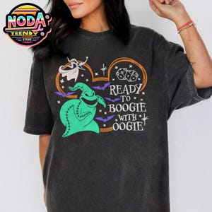 May include: Dark gray t-shirt featuring a green Oogie Boogie character and the text "Ready to Boogie with Oogie." The design includes bats, dice, and a ghost. The shirt has a vintage, distressed look.