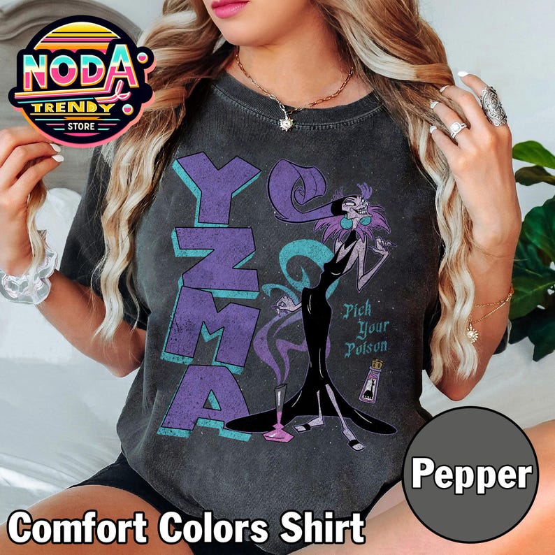 Pu&ograve; includere: Maglietta grigio scuro Comfort Colors con una grafica di Yzma da Le follie dell'imperatore. La maglietta presenta la parola "Yzma" in lettere viola e la frase "Pick Your Poison".