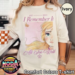 Puede incluir: Camiseta Comfort Colors marfil con el texto "I Remember It" y "All Too Well" con una ilustraci&oacute;n de dibujos animados de una mujer. La camiseta tambi&eacute;n tiene el texto "EST 2013".