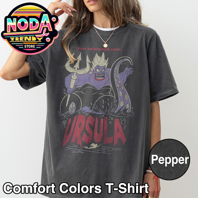 May include: Dark grey Comfort Colors T-shirt featuring a graphic of Ursula from The Little Mermaid. The design includes Ursula, a trident, and the text "URSULA". The shirt also has the text "Foor unfortunate souls."