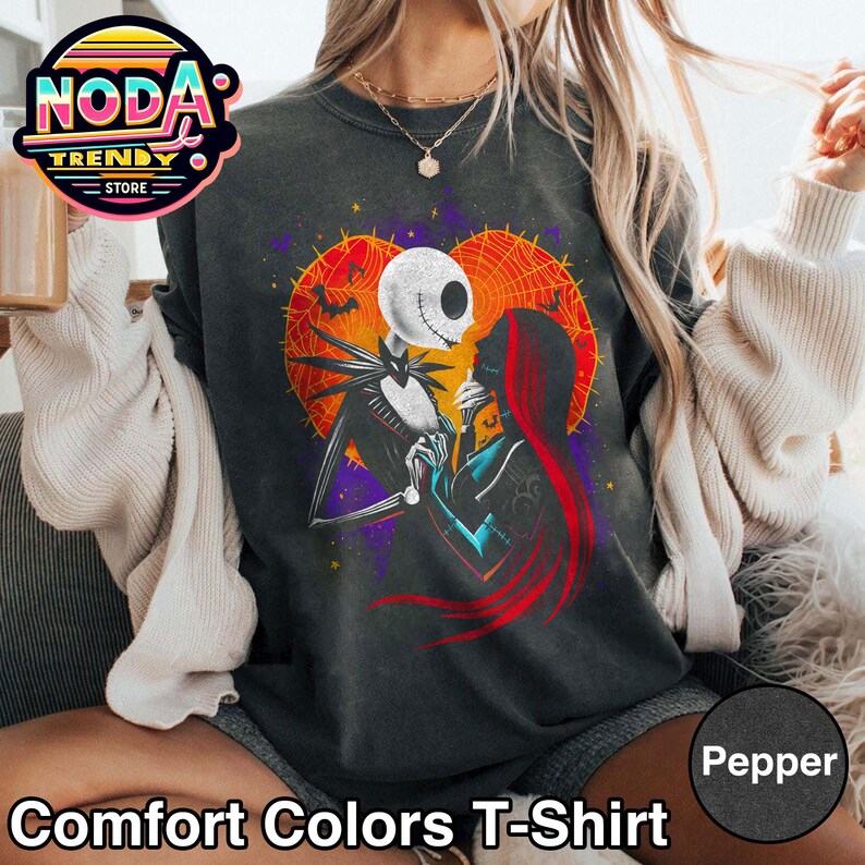 以下が含まれることがあります： ダークグレーのComfort Colors Tシャツ。映画「ナイトメアー・ビフォア・クリスマス」のジャック・スケリントンとサリーのロマンチックなイラストが特徴です。デザインには、コウモリとクモの巣のハート型の背景が含まれています。シャツには「Pepper」と表示されています。