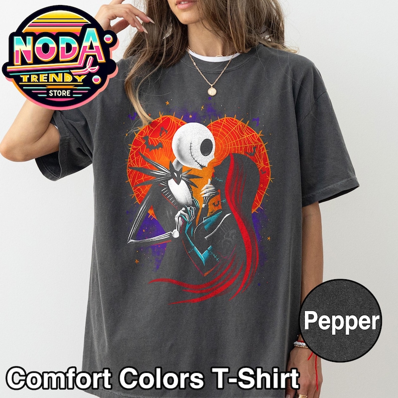 以下が含まれることがあります： 「ナイトメアー・ビフォア・クリスマス」のジャック・スケリントンとサリーのグラフィックが特徴のペッパーカラーのコンフォートカラーズTシャツ。デザインには、クモの巣とコウモリのハート型の背景が含まれています。シャツには「Comfort Colors T-Shirt」の文字が入っています。