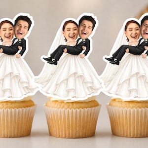 Puede incluir: Tres adornos para cupcakes con una novia en vestido blanco y un novio en esmoquin negro de estilo caricatura. El novio lleva a la novia en brazos. Cada adorno muestra un rostro fotográfico realista sobre el cuerpo ilustrado de dibujos.