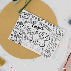 K&ouml;nnte beinhalten: Eine Schwarz-Wei&szlig;-Malvorlage mit dem Text "HAPPY BIRTHDAY Casper" und Illustrationen von Welpen, einem Hundeh&uuml;tte, Pfotenabdr&uuml;cken und einem Kuchen. Enth&auml;lt ein Wortsuchr&auml;tsel und Tic-Tac-Toe.