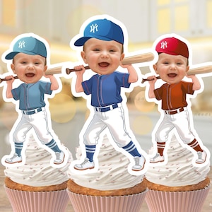 May include: Three cupcake toppers depicting cartoon babies in baseball uniforms, each holding a bat. The babies wear blue, navy, and red caps. The cupcakes have white icing and are in pink cupcake cases. The text "DIGITAL FILE MADE TO ORDER" is visible.