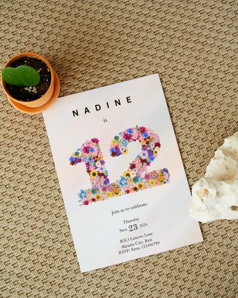 May include: A floral invitation card with the text "NADINE is 12" in a white font on a light pink background. The number 12 is made of colorful flowers. The invitation includes the date "Nov. 23, 2024", the address "B3L3 Lancers Lane, Alesana City, Reis", and the RSVP information "RSVP: Anna 123456789".