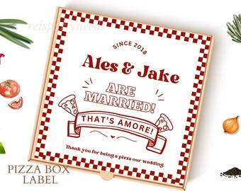May include: A white pizza box label with a red and white checkered border. The text reads "Since 2018 Ales & Jake Are Married! That's Amore!" with a pizza graphic. The text "Thank you for being a pizza our wedding" is below the graphic. The label also says "Pizza Box Label" at the bottom.