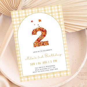 May include: A fall-themed birthday invitation with a gingham pattern background. The number "2" is formed from autumn leaves. The invitation includes the text "Join us to celebrate Mila's 2nd Birthday" and event details.