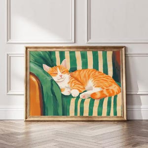Pode incluir: Uma obra de arte emoldurada retrata um gato laranja dormindo em uma superfície listrada verde e amarela. O gato está enrolado, com os olhos fechados, com uma expressão serena. A obra de arte está em uma moldura dourada.