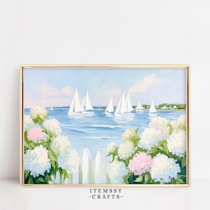 May include: Framed artwork featuring a coastal scene with sailboats on blue water under a light blue sky. White and pink hydrangeas frame a white picket fence in the foreground. The artwork is in a gold frame.