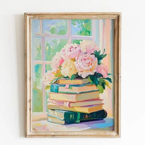 Op de afbeelding: Een ingelijst schilderij toont een stapel boeken met een boeket roze en gele pioenrozen. De boeken zijn in verschillende kleuren, waaronder groen, blauw en geel. De achtergrond toont een raam met uitzicht op groen en een zacht pastelkleurenpalet.