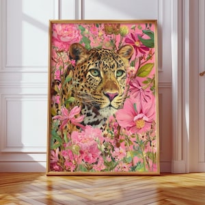 May include: A framed art print featuring a leopard amidst a vibrant display of pink flowers and foliage. The leopard has a spotted coat, green eyes, and a pink nose. The artwork is set against a pink background, creating a striking contrast.