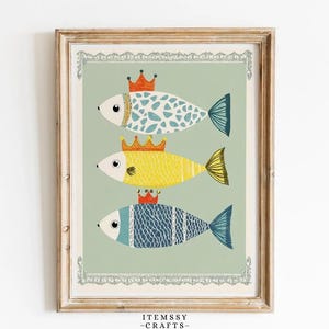 May include: A framed art print depicting three fish wearing crowns. The fish are in blue, yellow, and white, set against a pale green background with a decorative border. The print is in a wooden frame, suitable for a child's room.