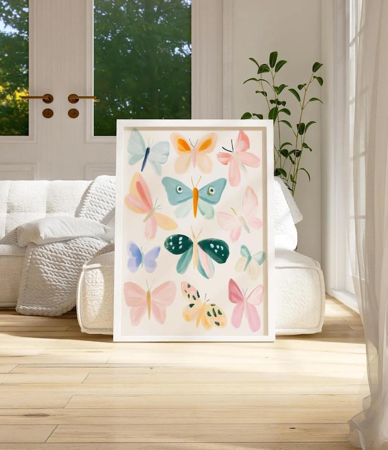 May include: A framed art print featuring a collection of colorful butterfly illustrations. The butterflies are depicted in various pastel shades, including pink, blue, and yellow, against a cream background. The artwork is encased in a white frame and displayed indoors.