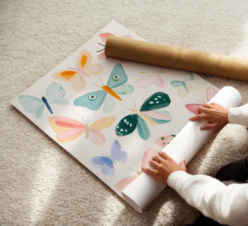 May include: A large sheet of paper with watercolor butterfly illustrations in pastel colors. The butterflies are in shades of blue, pink, orange, and green. A rolled-up paper tube is next to the sheet.