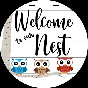 Puede incluir: Letrero de bienvenida con la inscripción "Welcome to our Nest" y tres búhos, uno azul, uno marrón y uno rojo, posados en una rama.