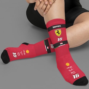 Puede incluir: Calcetines rojos con el logo de Ferrari, un escudo amarillo con un caballo negro y el número 16. Los calcetines también presentan logotipos de patrocinadores y detalles en negro. Fabricados con un material suave y cómodo.