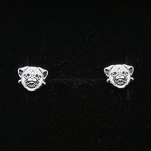 May include: A pair of silver stud earrings featuring a pug dog design.