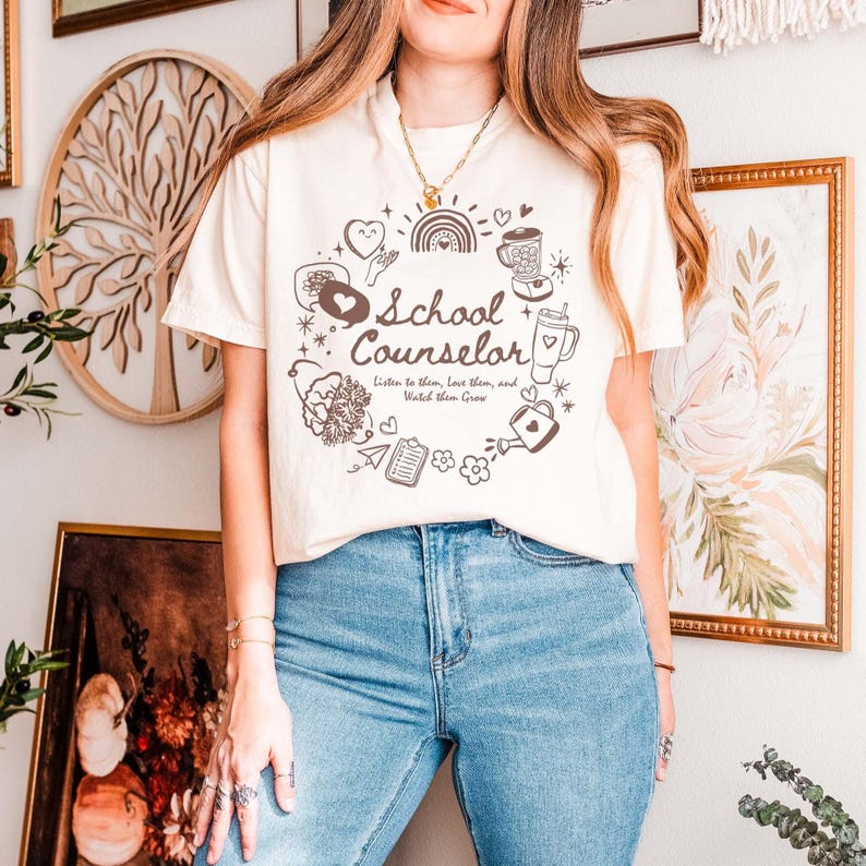 May include: A white t-shirt with a brown graphic design that says "School Counselor" with a heart and other illustrations. The text below the title says "Listen to them, Love them, and Watch them Grow."