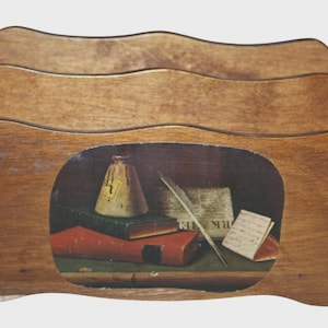 May include: A wooden letter holder with three wavy-edged compartments. The front panel features a printed still-life image of a tan ink bottle, a green book, a red book, a white feather quill, a newspaper, and a small handwritten note.