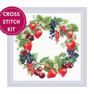 May include: Cross stitch kit featuring a wreath design. The wreath is composed of red strawberries, cherries, and currants, along with green leaves and white flowers. The text "CROSS STITCH KIT" is in a pink circle.