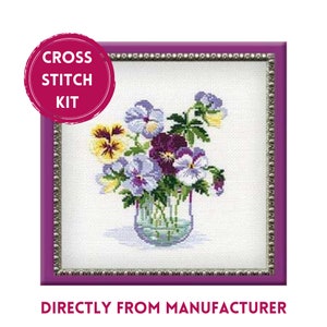 May include: A cross stitch kit featuring a floral design of pansies in a glass vase. The pansies are in shades of purple, yellow, and white, set against a white background. The image is framed in a purple border, with text that reads "CROSS STITCH KIT".