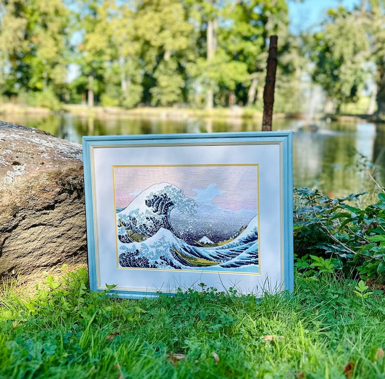 The RIOLIS cross stitch kit The Great Wave off Kanagawa after K. Hokusai Artwork features a detailed design using 17 colors of Anchor stranded cotton threads. The kit includes a needle, Zweigart 14ct white AIDA fabric, and a color chart.