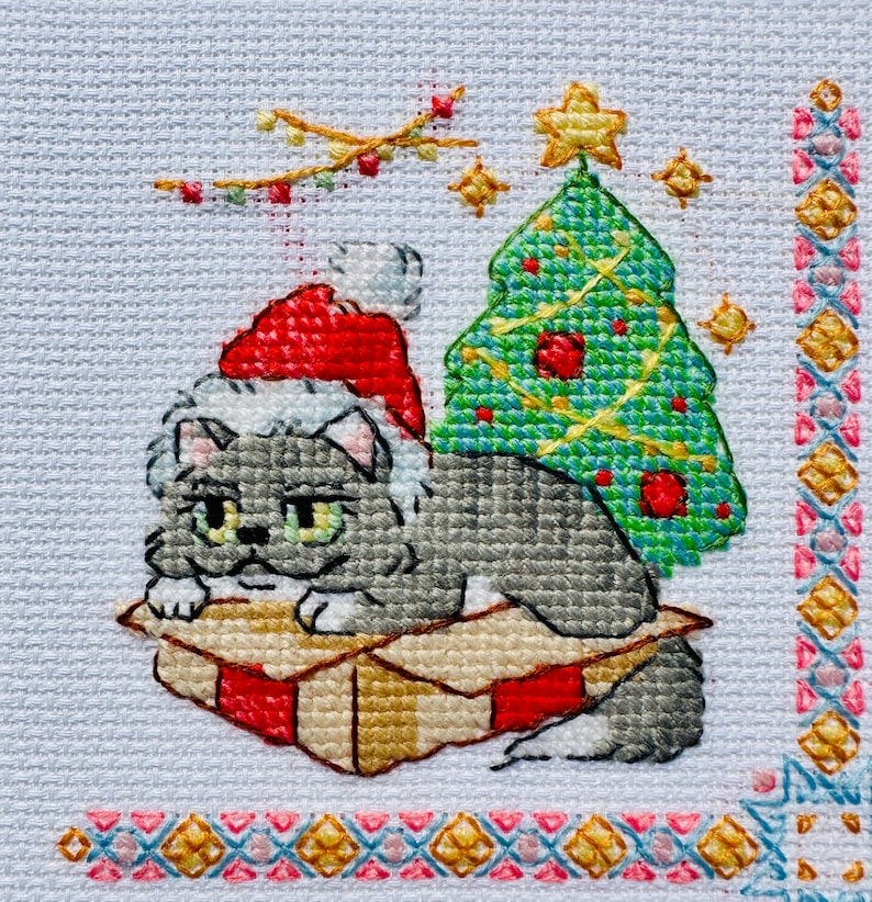 The RIOLIS cross stitch kit Cat Calendar features a charming calendar design with cats, using 29 colors of wool/acrylic threads. The kit includes a needle, Zweigart 14ct white AIDA fabric, and a color chart. The finished size is 30x40 cm.