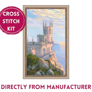 May include: Cross stitch kit featuring a detailed image of a pink castle on a cliff overlooking the ocean. The sky is a soft blue with pink and orange clouds. The castle has a tall tower and many windows. The kit includes all the materials needed to complete the project.