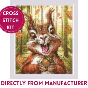 May include: Cross stitch kit featuring a cartoon squirrel holding an acorn, set against a forest backdrop with falling leaves. The squirrel has a wide, toothy grin. The text "CROSS STITCH KIT" is in a pink circle.