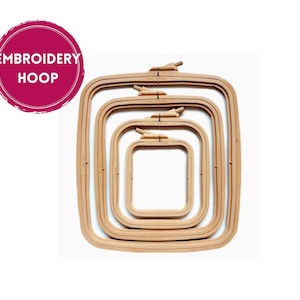 Può includere: Un set di quattro telai da ricamo quadrati in legno di diverse dimensioni. Ogni telaio ha una finitura in legno naturale e un meccanismo di serraggio. L'immagine include un cerchio rosa con la scritta "EMBROIDERY HOOP".