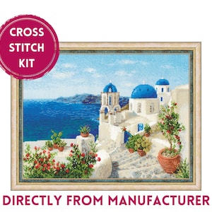 May include: Cross stitch kit featuring a colorful depiction of a white building with blue domes, set against a backdrop of a blue ocean and a clear sky. The building is surrounded by lush greenery and flowers.