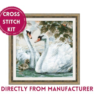 May include: Cross stitch kit featuring a framed image of two white swans and a cygnet swimming in a pond. The swans are in a romantic pose, with their necks intertwined. The image is surrounded by a gold frame.