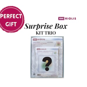 Könnte beinhalten: Ein Riolis Surprise Box Kit Trio mit drei Kreuzstich-Sets in einer rechteckigen Schachtel. Die Verpackung zeigt das Riolis-Logo, den Text Surprise Box KIT TRIO und ein großes schwarzes Fragezeichen auf der Vorderseite des kleineren Sets.