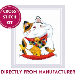 May include: Cross stitch kit featuring a white, calico, and orange cat holding a gold fish. The cat is sitting on a red cushion with a gold coin on its paw. The kit includes "CROSS STITCH KIT" text.