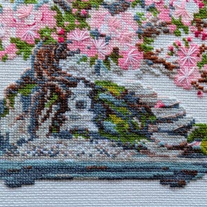 The RIOLIS cross stitch kit Flowering Bonsai features a delicate bonsai design using 17 colors of wool/acrylic threads. The kit includes a needle, Zweigart 14ct white AIDA fabric, and a color chart. The finished size is 30x24 cm (11¾in x 9½in).