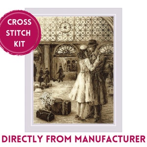 May include: A cross stitch kit featuring a sepia-toned image of a couple embracing in a train station. The couple is standing in the foreground, with luggage and other passengers in the background. The image is framed with a white border.