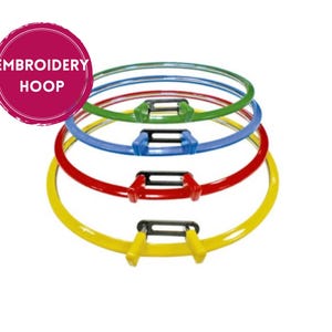 Puede incluir: Aro de bordado en varios colores: amarillo, rojo, azul, verde y transparente. Cada aro tiene un cierre en blanco y negro. La imagen incluye un círculo rosa con el texto "EMBROIDERY HOOP".