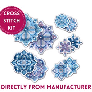 Può includere: Kit di punto croce con otto motivi a fiocco di neve in tonalità di blu e viola. Il kit include il testo "Cross Stitch Kit" in un cerchio rosso.