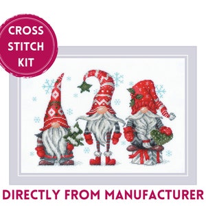 May include: Cross stitch kit featuring three gnomes wearing red and white hats with white beards. The gnomes are standing in a snowy scene with snowflakes.