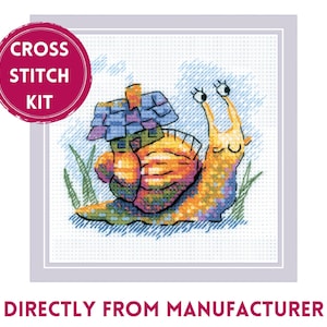 May include: Cross stitch kit featuring a whimsical snail with a house on its back, rendered in a cross-stitch style. The snail is in shades of yellow, orange, and blue, with green grass and a blue sky background. The text "CROSS STITCH KIT" is in a pink circle.