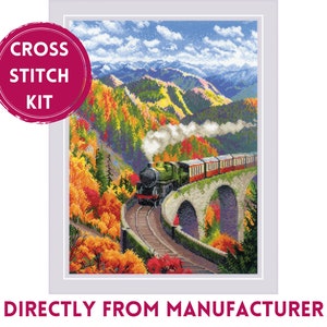 May include: Cross stitch kit featuring a train traveling through a mountain valley with fall foliage. The train is green and black with white smoke coming from the engine. The mountains are in the background and the sky is blue with white clouds.