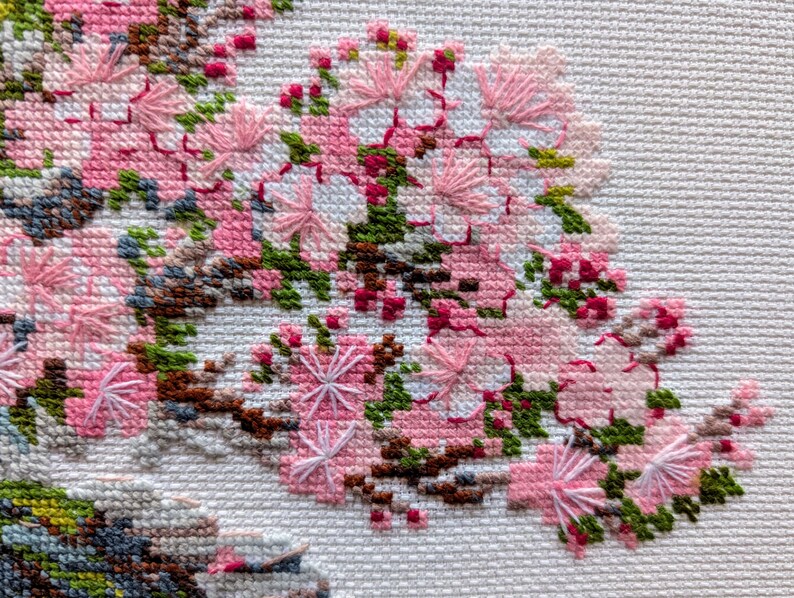 The RIOLIS cross stitch kit Flowering Bonsai features a delicate bonsai design using 17 colors of wool/acrylic threads. The kit includes a needle, Zweigart 14ct white AIDA fabric, and a color chart. The finished size is 30x24 cm (11¾in x 9½in).