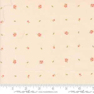 May include: A cream-colored fabric with a repeating pattern of small pink flowers and green leaves. The fabric is marked with a ruler in inches and the word "moda" appears twice on the ruler.