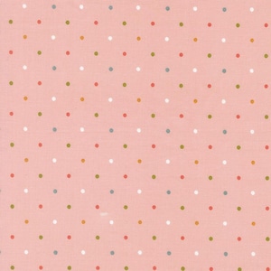 May include: Pink fabric with a repeating pattern of small, evenly spaced polka dots in various colors, including white, red, green, and blue. The fabric has a slightly textured appearance.