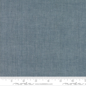 May include: A close-up of a blue denim fabric with a subtle texture. The fabric is measured with a ruler in inches.