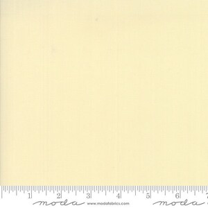 May include: A solid, pale yellow fabric swatch with a subtle texture. The fabric is measured in inches with a ruler.
