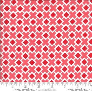 May include: White fabric with a repeating pattern of red and pink squares and crosses. The fabric is marked with a ruler in inches.