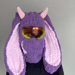 Puede incluir: M&aacute;scara de esqu&iacute; de punto morado y rosa con orejas de conejo largas y gafas de esqu&iacute;.